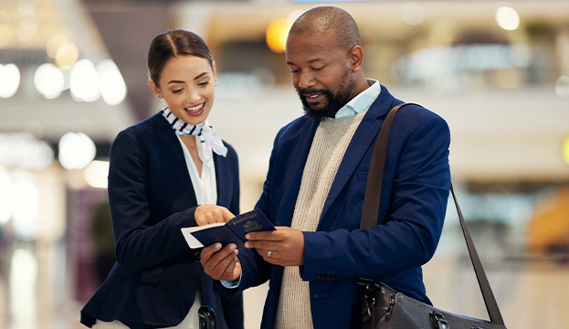 A professional female service agent in a uniform helping a businessman review his passport documents, demonstrating specialized OTA-trained customer support.