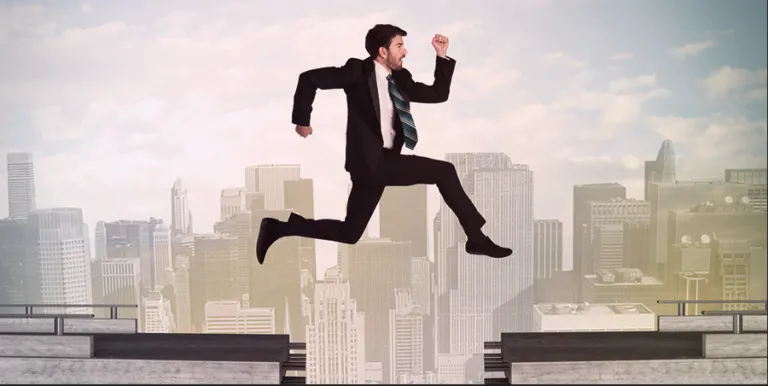 Businessman leaping between rooftops over a city skyline