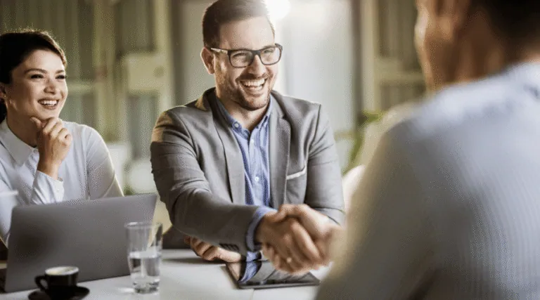 Business partners shaking hands across a meeting table