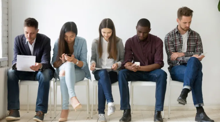 Young people sitting in a row looking at their phones