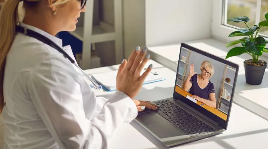Agent waving on a live video chat with a customer on a laptop