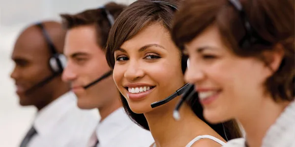 Three smiling call center agents in headsets