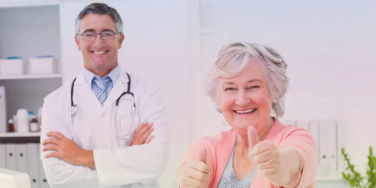 Smiling doctor and senior woman giving a thumbs up