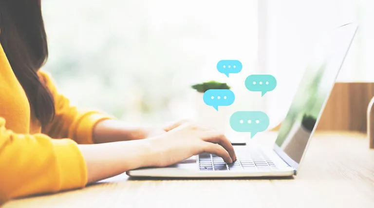 Person typing on a laptop with chat message bubbles
